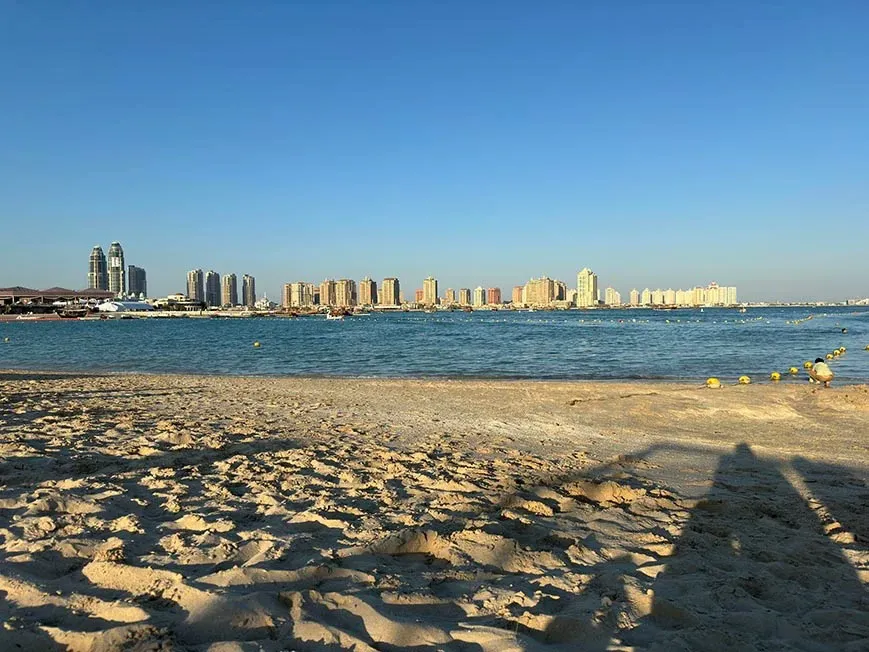 A middle eastern beach with a city scape and apartment buildings in the distance