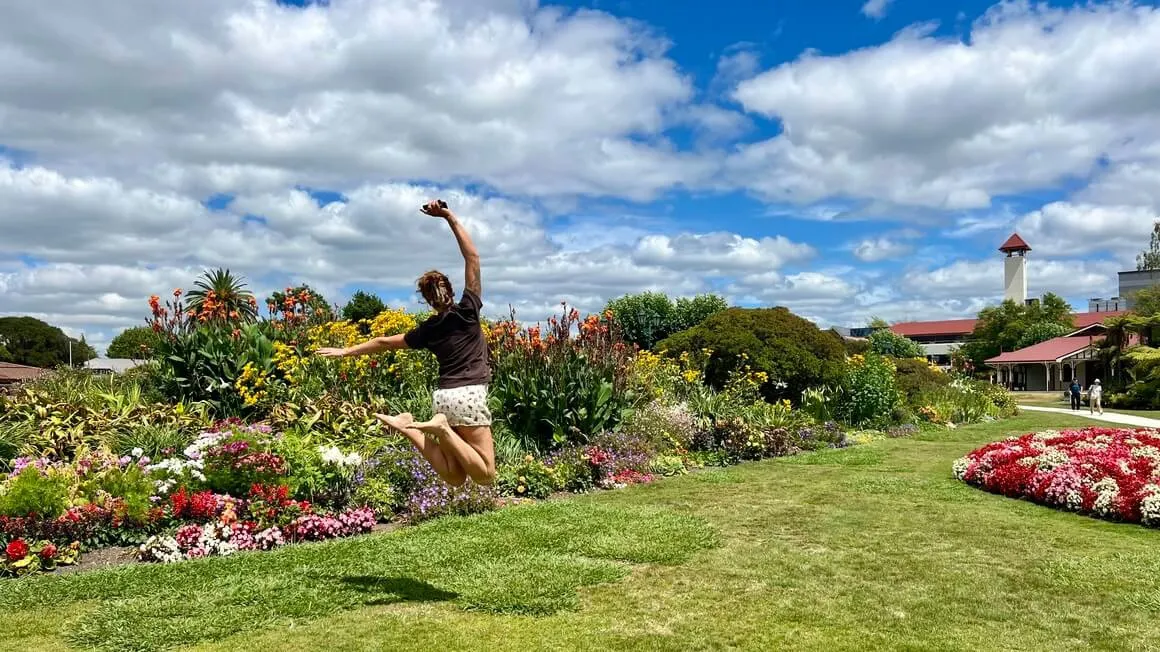 Girl jumping in front of a flower garden in Rotorua government gardens, New Zealand