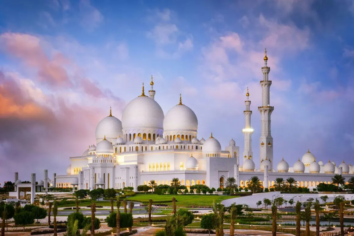 sheikh zayed grand mosque iwth a cotton candy sunset sky in the background