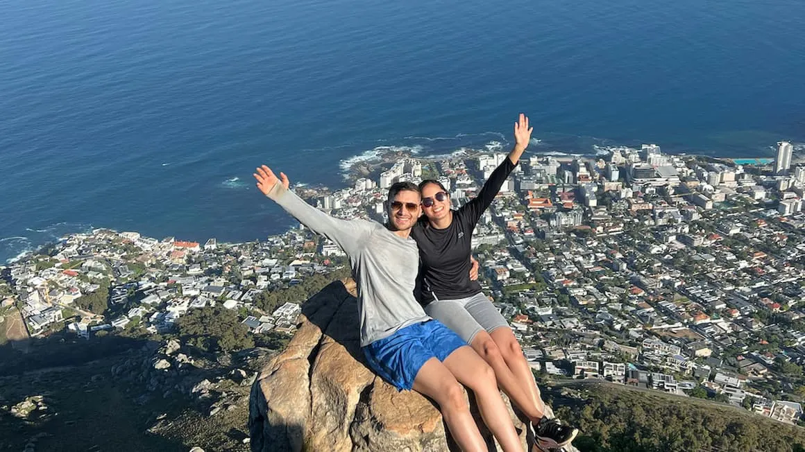 two friends hiking to a viewpoint in cape town, South Africa. View of the city along the sea shore