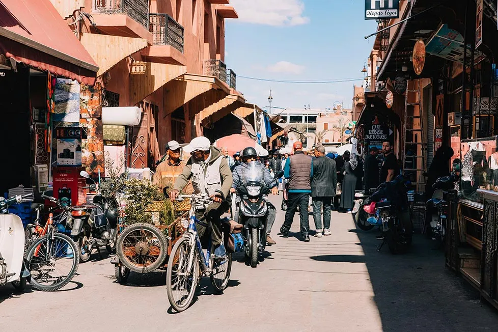 A busy street with people, motorbikes and shops in the medina in Marrakech, Morocco.