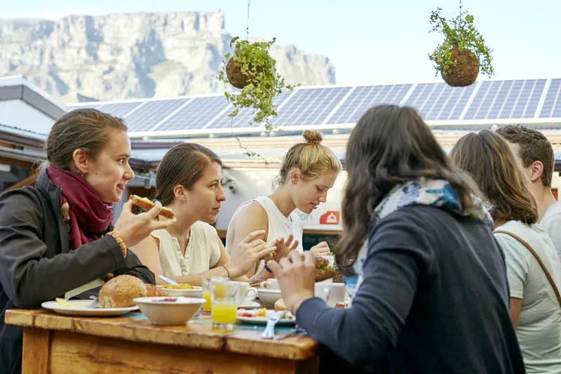 The Backpack Best Hostels in Cape Town. A group of friends sitting at the on site restaurant.