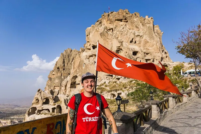 Nic next to Uchisar Castle with a turkey flag in Cappadocia