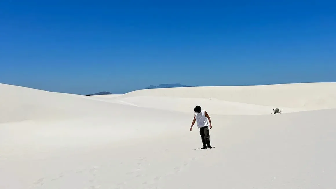 A guy standing in the middle of sand dunes n Cape Town, South Africa
