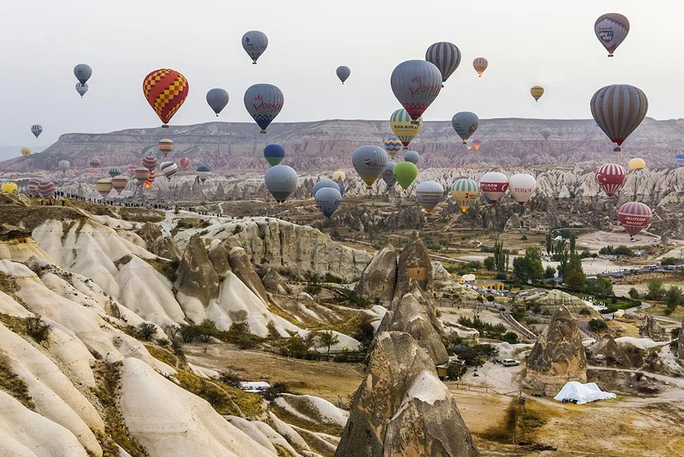 Hot air balloons rising above a valley of fairy chimney rock formations in Cappadocia, Turkey