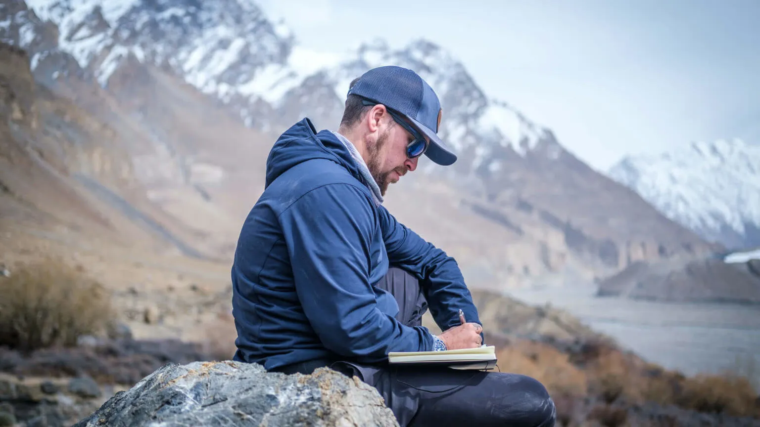 Will sitting in the mountains writing in his journal in Pakistan