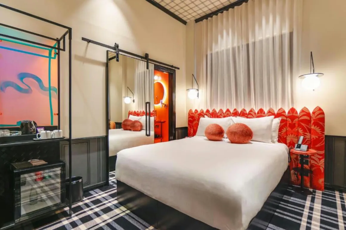 Naumi Studio bedroom with a large comfortable bed, red headboard and a black and white floor.